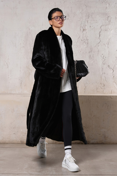 Stylish woman in a long black mink coat, showcasing luxury and versatility for both formal and sporty looks.