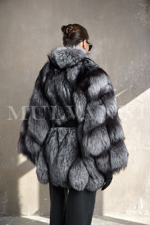 Wearing a plush silver fox fur coat with a cinched silhouette, the woman exudes luxury and warmth in arctic-ready style.