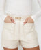 Woman wearing stylish white leather shorts with pockets and a belt.
